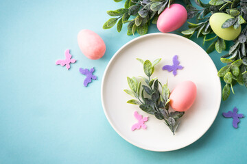 Easter table setting, Easter food background. White plate with eggs, spring flowers, green leaves...