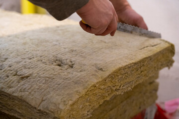 Man Skillfully Cutting Mineral Wool with Expertise and Care.