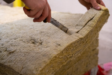 Masterful Precision: Hands Expertly Cutting Mineral Wool with a Specialized Knife.