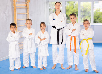 Fototapeta na wymiar With their instructor, children karate enthusiasts gather for group picture.