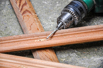 Man holding green drill and drilling lining woods, electric drill-driver