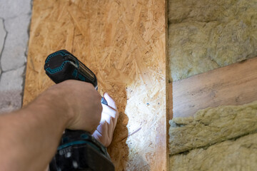 Efficient Craftsman Secures OSB Plate to Wooden Frame Using Precision Electric Tool.