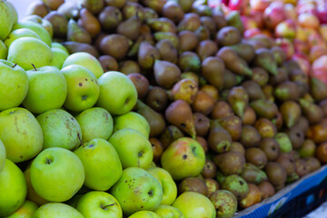 Ripe juicy green pears and apples in box on counter at supermarket. Fruit for sale