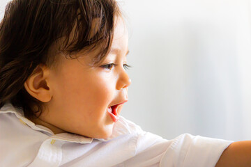Face of Hispanic Latino baby sitting with white shirt looking forward and raising left arm