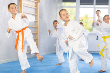 Fototapeta na wymiar Young karate students gather in dojo to practice their kicks and punches under the watchful eye of their sensei.