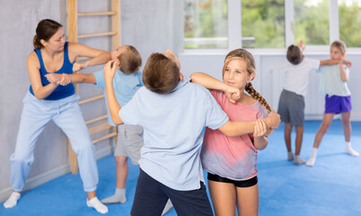 Purposeful engrossed children train during krav maga training session and work out basic elements...
