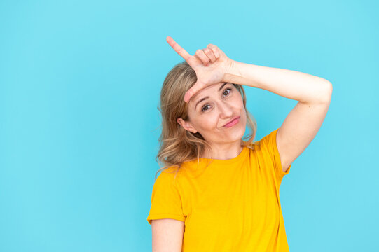 Woman doing loser gesture with fingers on forehead