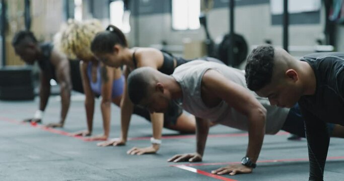 People, group and push ups in training for workout, exercise or team in practice for strength at gym. Man and woman lifting body weight for strong arms or performance at indoor health club together