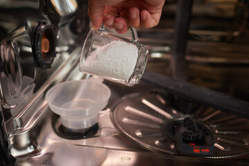 High-angle view of unrecognizable man using funnel to pour granulated salt to soften hard water...