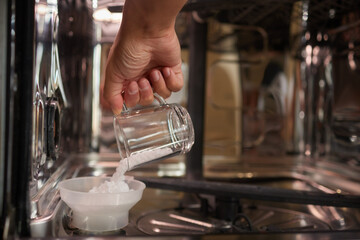 High-angle view of unrecognizable man using funnel to pour granulated salt to soften hard water...