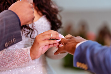 a couple holding hands exchanging rings at their wedding