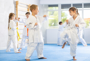 Karate kids in kimono sparring together during their group karate training