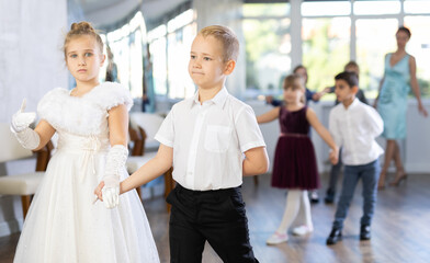 Fototapeta na wymiar Active preteen children practicing ballroom dances in pairs during dancing classes
