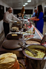 a waiter preparing crepes at a buffet table