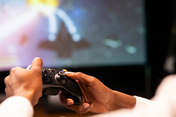 Close up shot of controller held by man playing galaxy flying videogame on smart TV, relaxing....