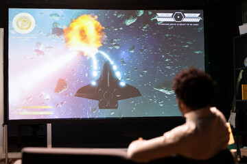 Man watching science fiction videogame gameplay footage on TV uploaded online by pro streamer....