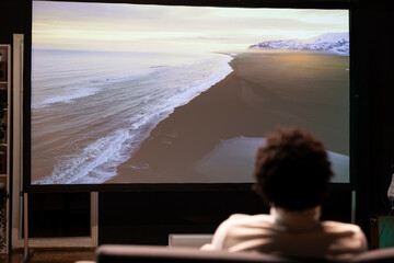 Man relaxing on sofa watching climate change documentary with beautiful cinematography on modern...