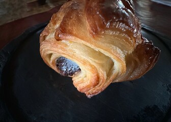 Chocolate filled croissant on a black background showing the flaky layers and soft chocolate filling