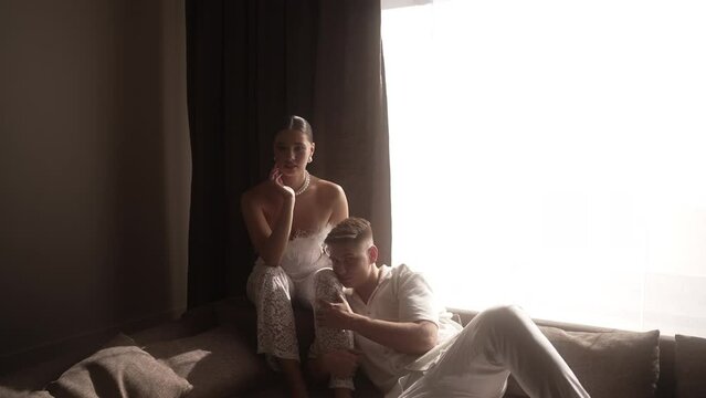 The bride and groom in pathetic poses are sitting on the bed