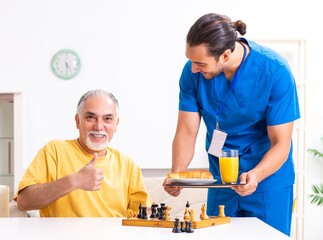Young male doctor visiting old patient at home
