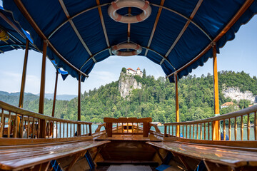 View through the traditional Pletna boat to Bled Castle on top of the rock with forest around, Slovenia, Bled