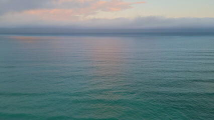 Rippling ocean surface reflecting beautiful sunset. Aerial view marine sunrise