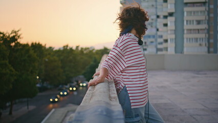 City girl posing sunset on roof. Carefree woman leaning on railings at evening