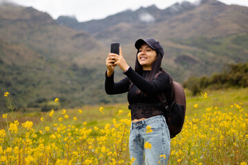 Retrato de una hermosa chica turista con gorra mirando el móvil en el hermoso paisaje, revisando...