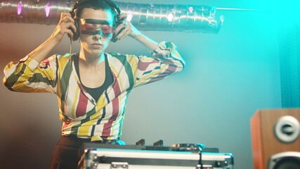 Woman performer mixing sounds at stereo turntables, using audio instruments and disco vinyl to play...