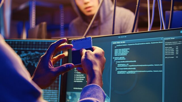 Close up shot on hacker holding SSD device with zero day exploit uploaded on it, able to go undetected by antivirus software installed on systems, showing it to fellow cracking group colleague