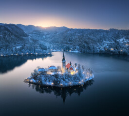 Aerial view of church on snowy island on the Bled Lake, Slovenia at winter night. Top drone view of...