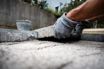 Worker placing cement tile to freshly pave a sidewalk or patio