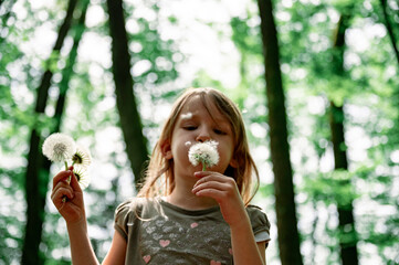 Toddler girl blowing gentle dandelion bulb - 716024665
