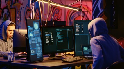 Malicious computer specialists in secret abandoned warehouse working together to get past anti...