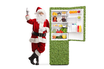 Santa claus leaning on a green eco-friendly fridge and pointing up