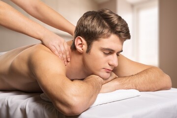 Handsome man has back massage in salon, relaxing after work.