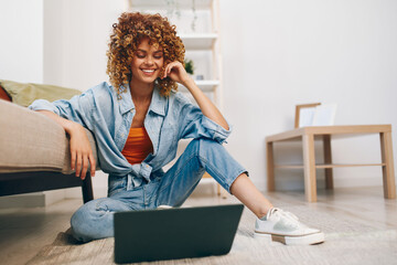 Smiling woman using laptop for online freelance job in a cozy living room.