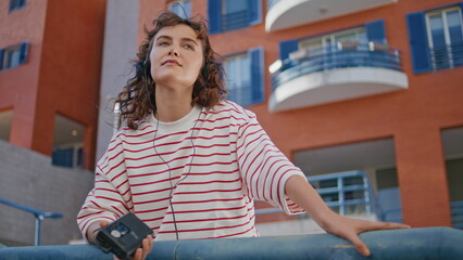 Girl holding cassette player listening music at urban area alone close up.