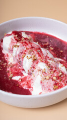 A plate of cheese fritters in cream-cherry sauce angle view on beige background
