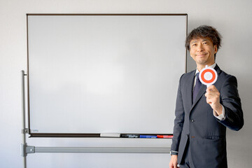 ボードの前で丸を出すスーツ男性
