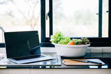 An open laptop with an empty screen against a background of healthy vegetables illustrating the...