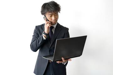 顔歪めるPCと電話を持った男性