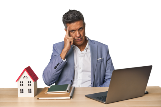 Middle-aged Hispanic businessman with real estate theme pointing temple with finger, thinking, focused on a task.