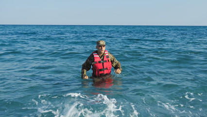 Fototapeta na wymiar Soldier with life jacket comes out of the sea