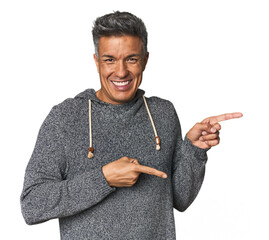 Middle-aged Latino man pointing with forefingers to a copy space, expressing excitement and desire.