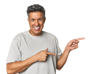Middle-aged Latino man pointing with forefingers to a copy space, expressing excitement and desire.