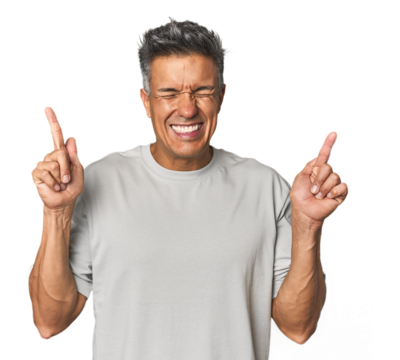 Middle-aged Latino man crossing fingers for having luck