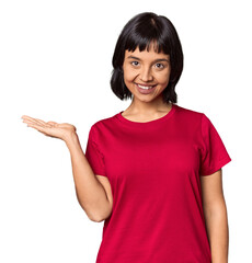 Young Hispanic woman with short black hair in studio showing a copy space on a palm and holding another hand on waist.