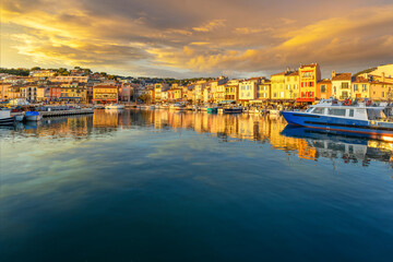 A dramatic sky at golden hour sunset above the seaside fishing village and resort town of Cassis,...