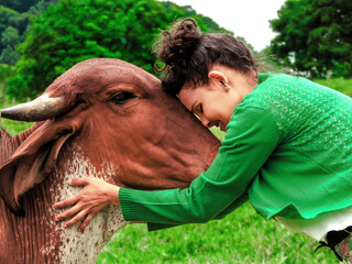 Harmony Unveiled: A bond beyond Species. Serene image of a young woman in a green sweater embracing...